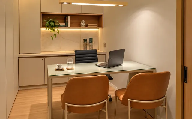 Consultório com mesa, cadeiras e prateleiras iluminadas